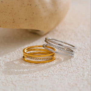 Two rings, one gold and one silver, on a textured surface.