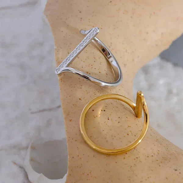 Minimalist 925 silver and 18K gold-plated rings displayed on a textured surface