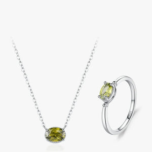 Silver necklace and matching ring set featuring an oval yellow-green gemstone, displayed on a clean white background.