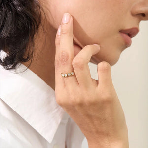 Close-up of a person wearing a delicate ring on a neutral background