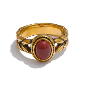 Gold ring with a red stone on a white background.