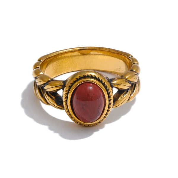 Gold ring with a red stone on a white background.
