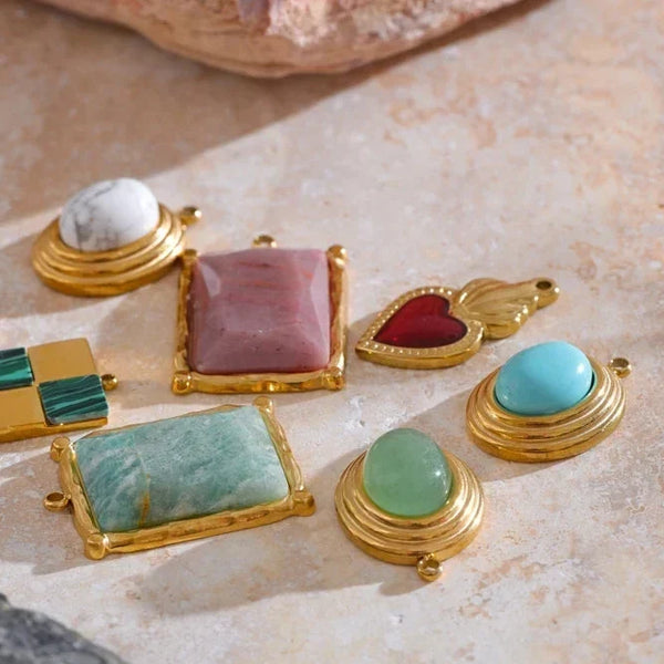 Collection of gold-rimmed gemstone jewelry pieces on a stone surface