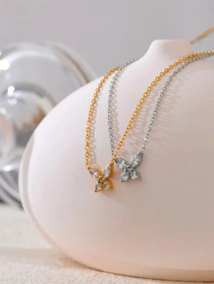 Two butterfly-shaped necklaces on a white mannequin bust with a blurred background.
