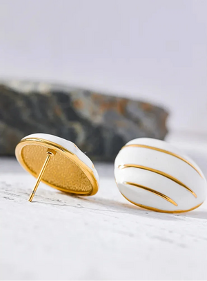 White earrings with gold accents on a light surface