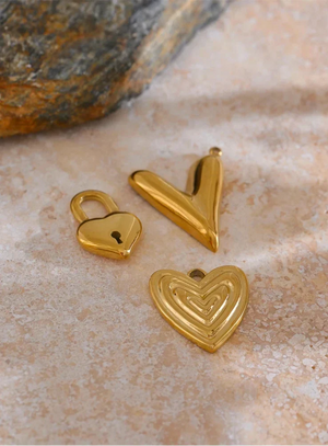 Three gold heart-shaped pendants on a textured surface