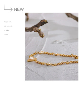 Gold chain bracelet with heart charm on a light background