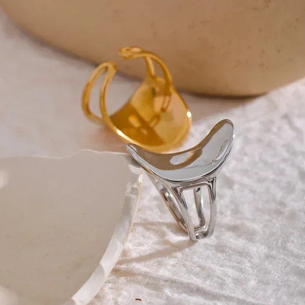 Minimalist silver and gold statement rings on a textured fabric background