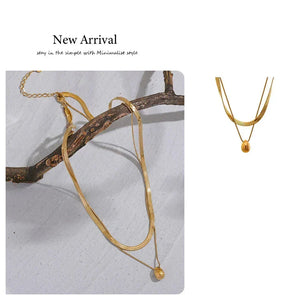 Gold necklace with a small pendant on a branch against a light background