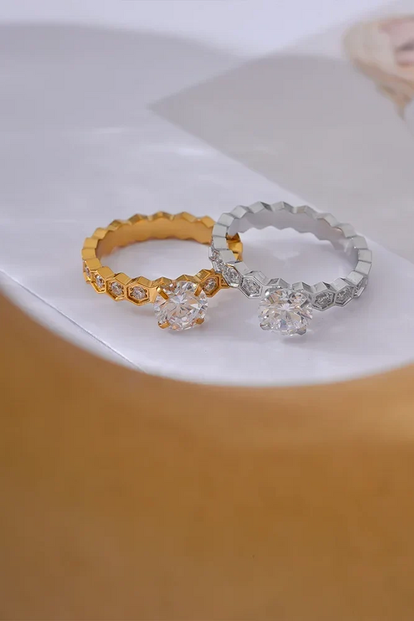 Two rings, one gold and one silver, on a white surface with a blurred background.