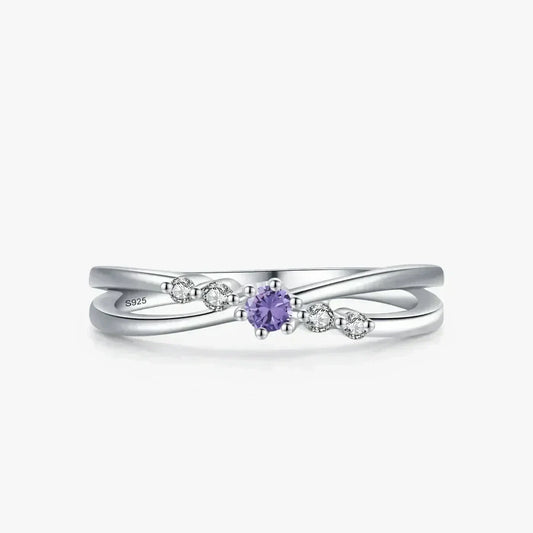 Sterling silver ring with twisted band, purple gemstone center, and small clear accent stones.