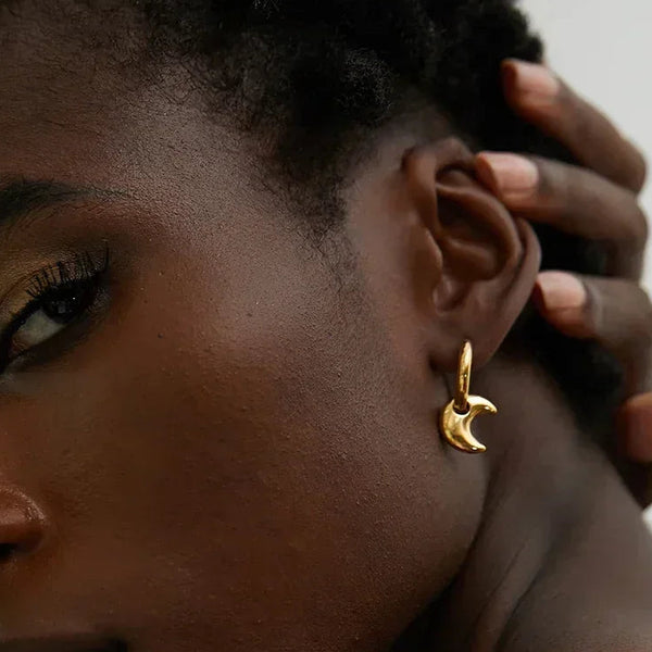 Close-up of a woman Astral Affection Hoops - TM & CO. JEWELS - a gold earring with a neutral background.