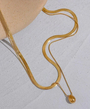 18K gold-plated herringbone chain necklace with teardrop pendant on light surface