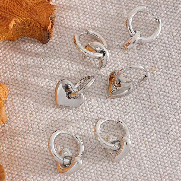 Silver hoop earrings on a textured beige surface with 'Vogue' branding.