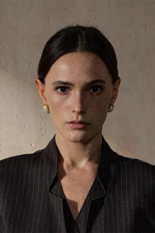 Woman wearing a black pinstripe shirt against a beige background