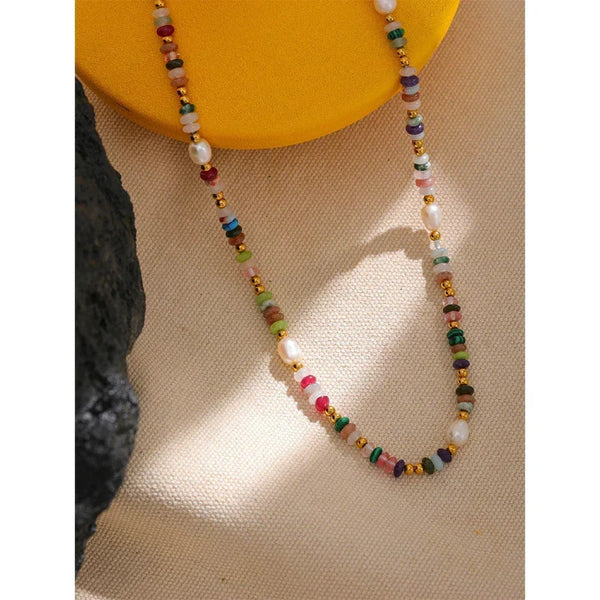 Nouveau Bohème Necklace - TM & CO. JEWELS beaded necklace on a textured surface with a yellow object in the background