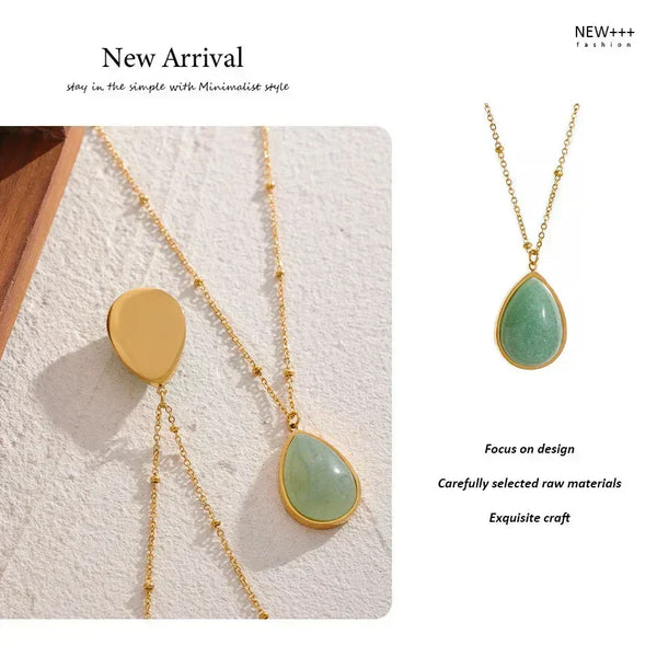Two necklaces with gold chains and green teardrop pendants on a textured white surface.