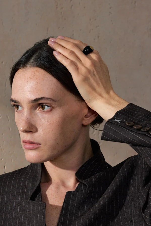 Person adjusting their hair against a neutral background