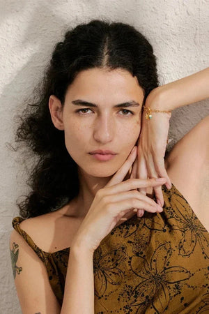 Woman with dark hair and a floral-patterned top against a neutral background