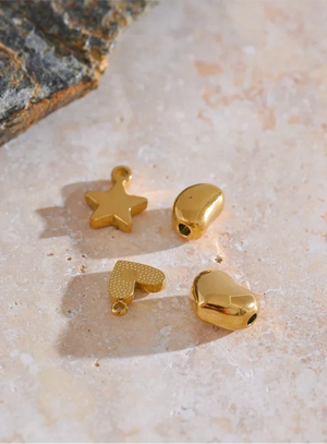 Gold jewelry charms on a textured stone surface