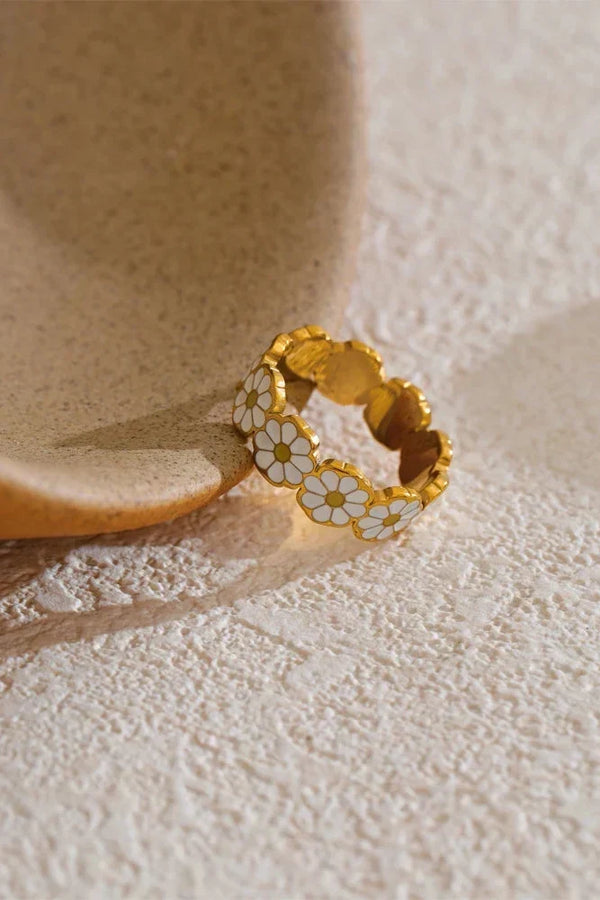 Gold ring with floral design on a textured surface