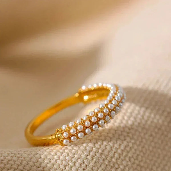 Gold-plated ring with rows of small pearls on beige textured fabric