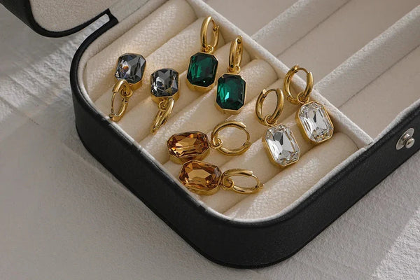 Set of gold and gemstone earrings in a jewelry box on a light surface