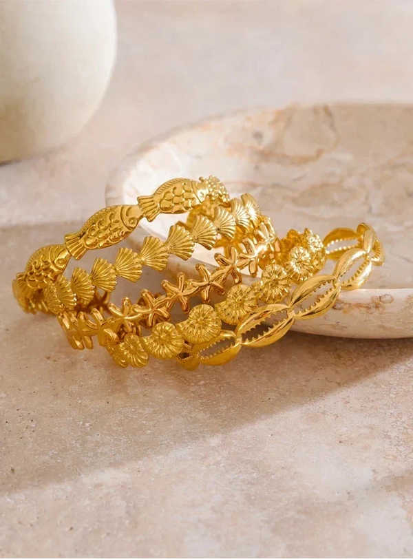 Gold bracelet with intricate designs on a beige surface