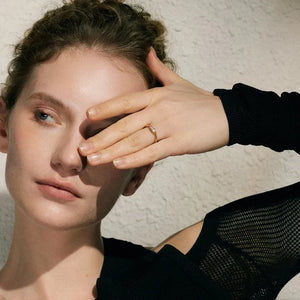 Woman with hand covering one eye against a textured wall.