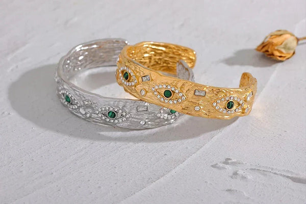 Gold and silver bangles with green gemstones on a light gray background, featuring the Vogue logo.