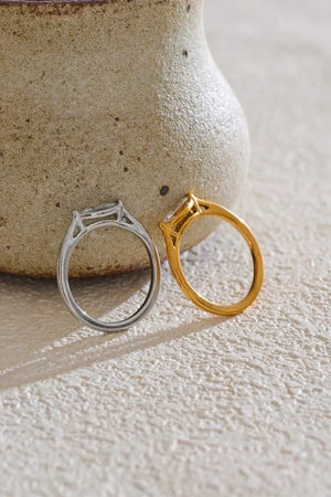 Gold and silver rings on a textured surface with a ceramic vase in the background