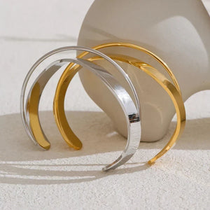 Two gold and silver bangles on a textured surface with a neutral background.