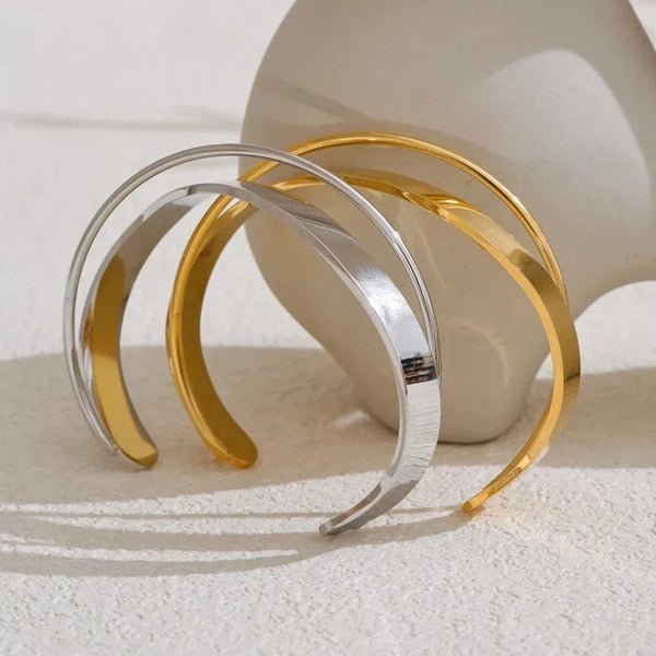 Two gold and silver bangles on a textured surface with a neutral background.