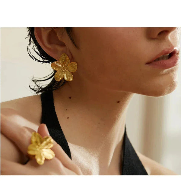 Woman wearing gold-plated flower earrings and matching ring, elegant jewelry close-up
