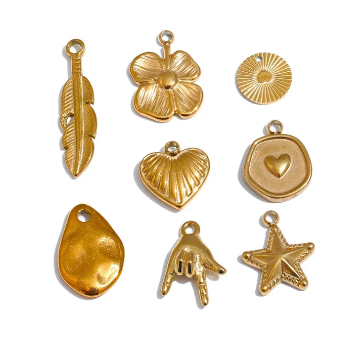 Gold jewelry charms including a feather, flower, heart, and star on a white background.