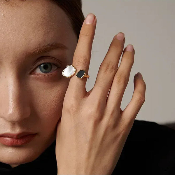 Woman wearing a gold-plated open ring with black and white stones, elegant jewelry
