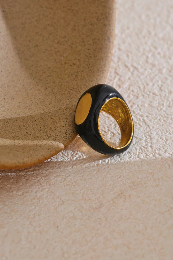 Black and gold ring on a textured beige surface