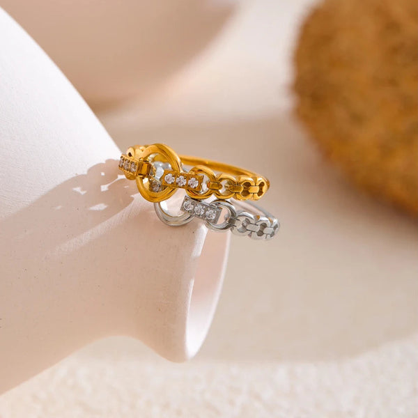 Gold and silver ring with interlocking design on a neutral background