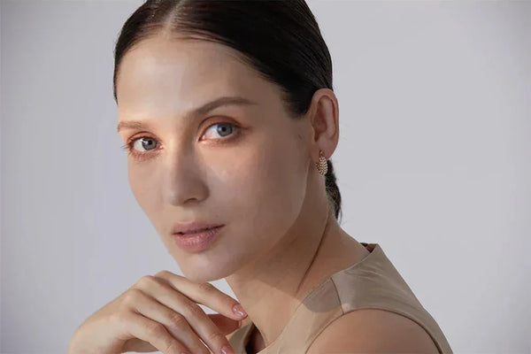 Woman wearing gold-plated, textured stud earrings, elegant jewelry close-up portrait