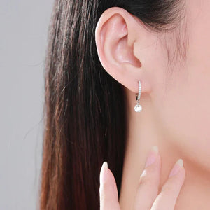 Close-up of an earring worn by a person with dark hair.