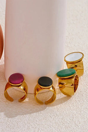 Set of gold rings with colorful gemstones on a textured surface