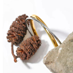 Gold and silver bracelet on a stone background with 'NEW++' branding.