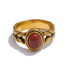 Gold ring with a red stone on a white background