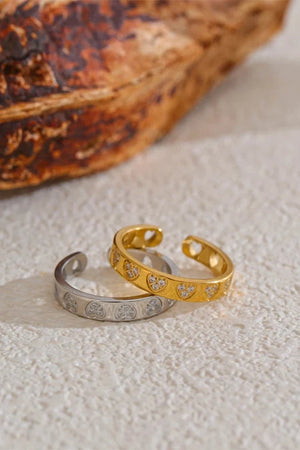 Two gold and silver toe rings on a textured surface with a woven basket in the background.