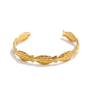 Gold bracelet with fish design on a white background