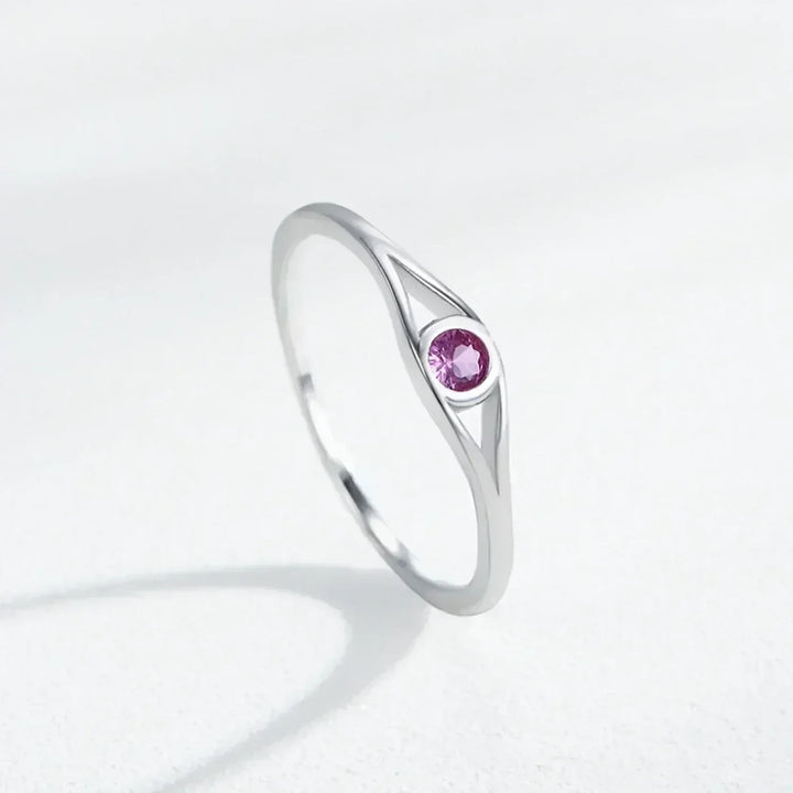 Silver ring with a pink gemstone on a light gray background