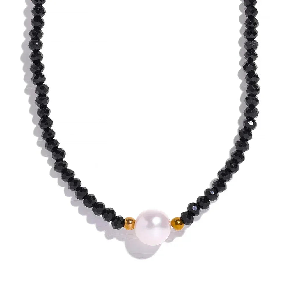 Necklace with black beads and a pink pearl pendant on a white background.
