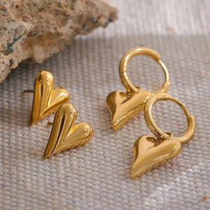 Gold heart-shaped earrings on a textured surface with 'HAPPY EVERYDAY' branding.