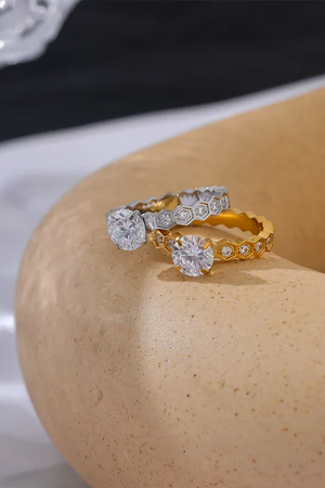 Two diamond rings on a beige stone surface