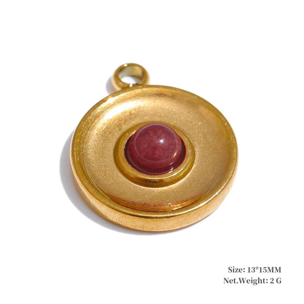 Gold pendant with a red gemstone on a white background